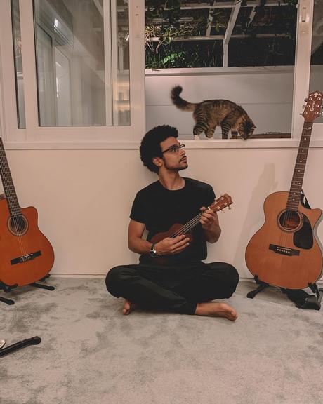 Sérgio Malheiros posa ao lado de seu gato enquanto toca ukulele