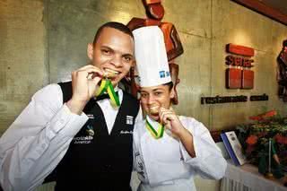 Hemilton Heverton dos Santos e Laysa Menezes, estudantes do Senac Bahia, brincam com as medalhas conquistadas na Olimpíada do Conhecimento 2010 e World Skills Américas, nas categorias Cozinha e Serviço de Restaurante, respectivamente. - ANDRÉ ZÍMMERERE, DANIEL NOGUEIRA, F22 STUDIO FOTOGRÁFICO, GUILHERME PUPO, JADER DA ROCHA, RONNY CAJANGO E WELTON ARAÚJO