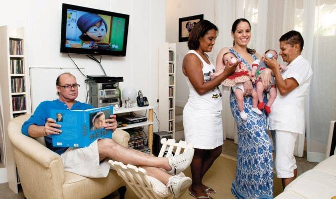 Paulo César lê sobre bebês, enquanto Cláudia tem a ajuda de Gegê e Lilita para dar mamadeira aos gêmeos de 4 meses, na casa da família, Rio. - FOTOS: SELMY YASSUDA; BELEZA: DUH