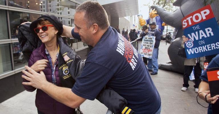 Sorridente, Susan ganha, para se aquecer, jaqueta de manifestante, que faz questão de ajudar a atriz a vesti-la. - Splash News