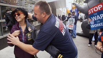 Sorridente, Susan ganha, para se aquecer, jaqueta de manifestante, que faz questão de ajudar a atriz a vesti-la. - Splash News