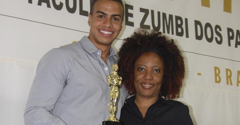 O jornalista e apresentador Thiago Oliveira recebe seu Troféu Raça Negra 2011, na categoria Jornalismo Masculino, da diretora do prêmio, Ruth Lopes, em faculdade de São Paulo.