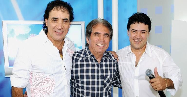 Em estúdio da RedeTV!, em Osasco, na Grande São Paulo, o apresentador Eli Corrêa é ladeado pela dupla sertaneja Roberto e Meirinho.