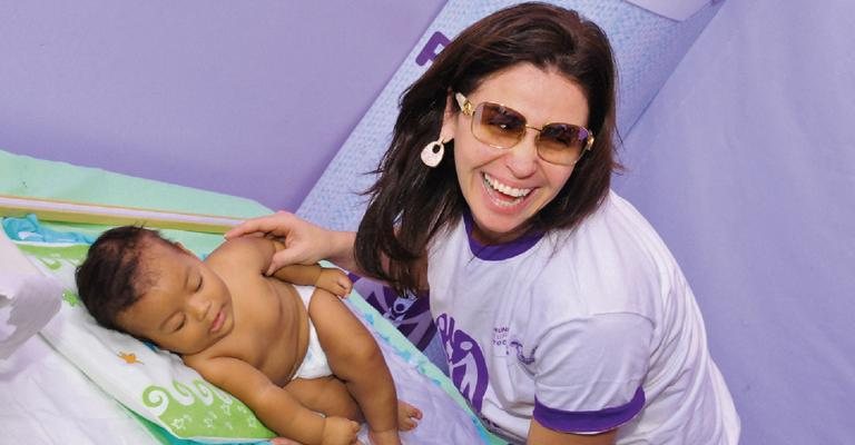 Sorridente, Giovanna mima bebê durante o lançamento de Prematuro Imunizado é Prematuro Protegido. - -