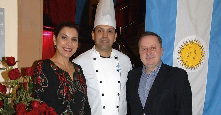 O chef Ricardo Sabbado prepara jantar argentino e é ladeado por Fabiana Costa e Rogério Poloni, em Gramado. - -