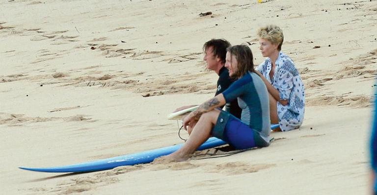 Com um amigo, Sean Penn e Charlize Theron apreciam o pôr do sol em praia na ilha de Oahu - AKM-GSI/AKM-GSI E Fam E Flynet/The Grosby Group