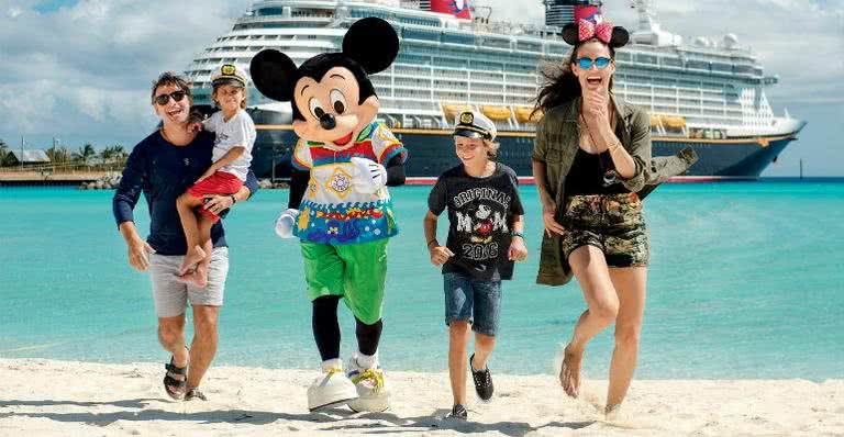 O casal e os filhos Artur, no colo do pai, e Lucas, são recebidos por Mickey na Castaway Cay - CHLOE RICE