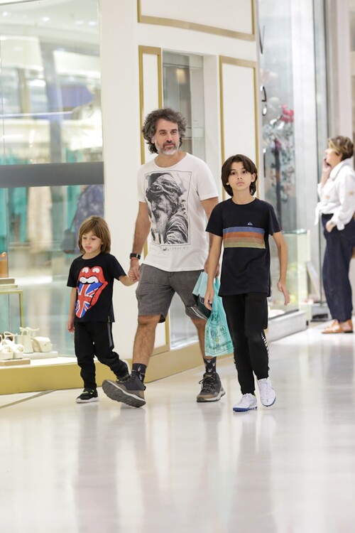 De mãos dadas com João e Gael, o pai caminhou com os filhos e apareceu segurando algumas sacolas durante o passeio. 