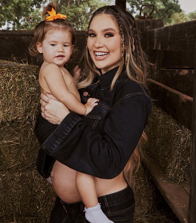 Virginia Fonseca em pé segurando a filha Maria Alice no colo enquanto olham para a câmera