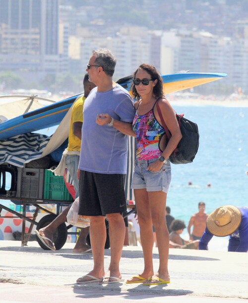 acompanhada do marido Márcio Farias e vestido um maiô colorido com uma bermuda jeans por cima da peça