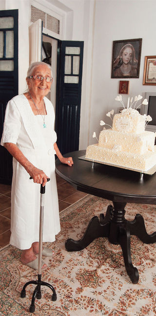 Elegante, vestida de branco, como costuma aparecer em festas, Dona Canô re