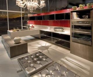 Com criatividade, esta cozinha aposta no contraste entre o antigo e o contemporâneo. O painel de fórmica vermelho, os pufes Barcelona de vinil metalizado da Clássica Design (classica.com.br), a bancada de silestone bege, os eletrodomésticos de aço inoxidá