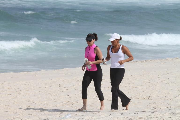 Giovanna Antonelli corre ao lado de amiga na praia da Barra da Tijuca