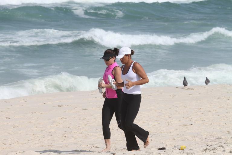 Giovanna Antonelli corre ao lado de amiga na praia da Barra da Tijuca