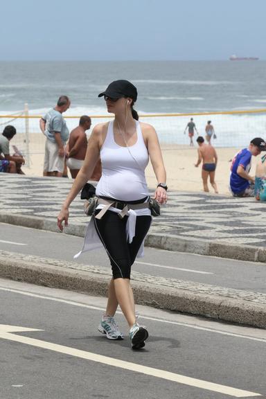 Grávida, Lavínia Vlasak caminha pela orla da praia do Leblon, no Rio de Janeiro