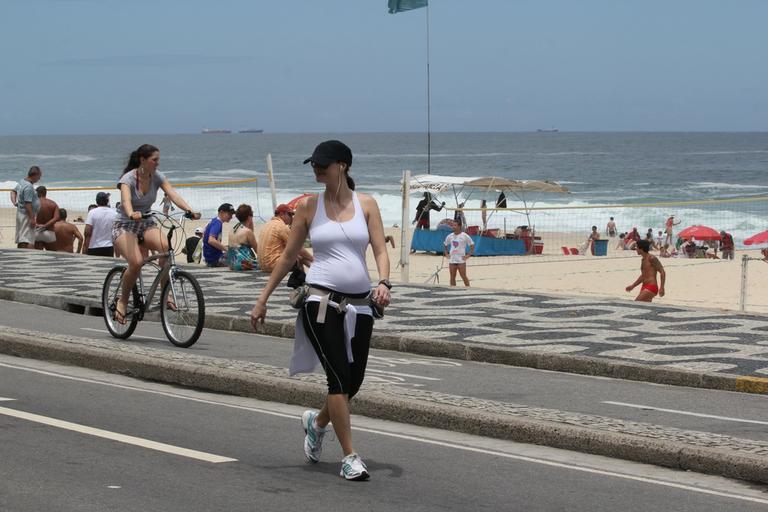 Grávida, Lavínia Vlasak caminha pela orla da praia do Leblon, no Rio de Janeiro