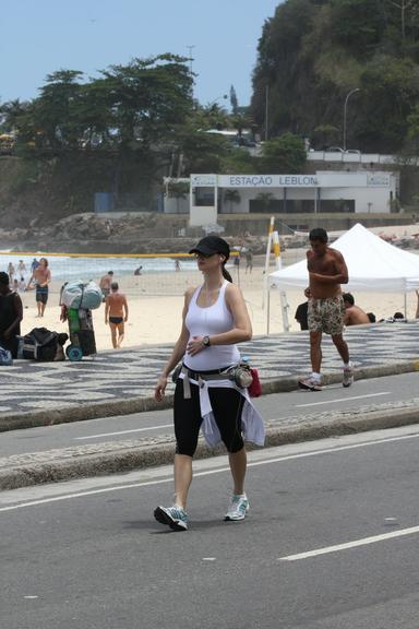 Grávida, Lavínia Vlasak caminha pela orla da praia do Leblon, no Rio de Janeiro