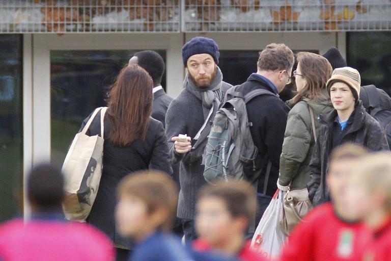 Jude Law ao lado de outros pais durante jogo do filho