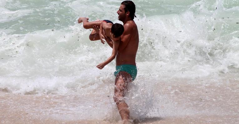 Henri Castelli brinca com o filho, Lucas, na praia