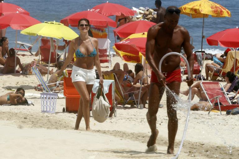 Cavalheiro molha areia quente para que Letícia Birkheuer caminhe