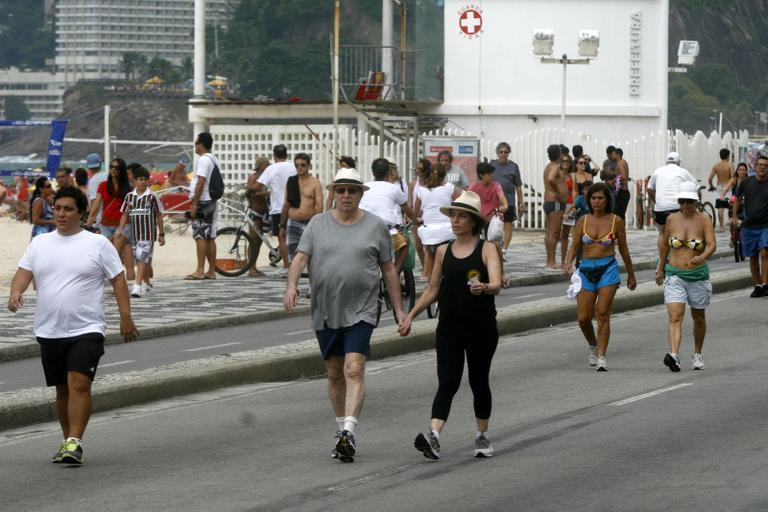 Daniel Filho caminha com a mulher, Olivia Byington, pela orla da praia de Ipanema