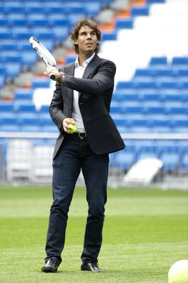 De terno e sapato, Rafael Nadal joga tênis no campo do Real Madrid