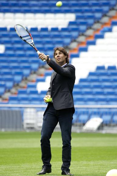 De terno e sapato, Rafael Nadal joga tênis no campo do Real Madrid