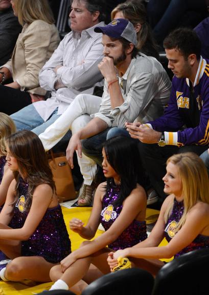 Ator Ashton Kutcher observa dançarinas em jogo dos Lakers em Los Angeles