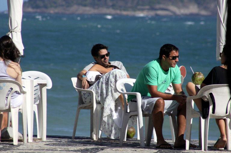 Bruno Mazzeo, com novo visual, e namorada na praia do Leblon