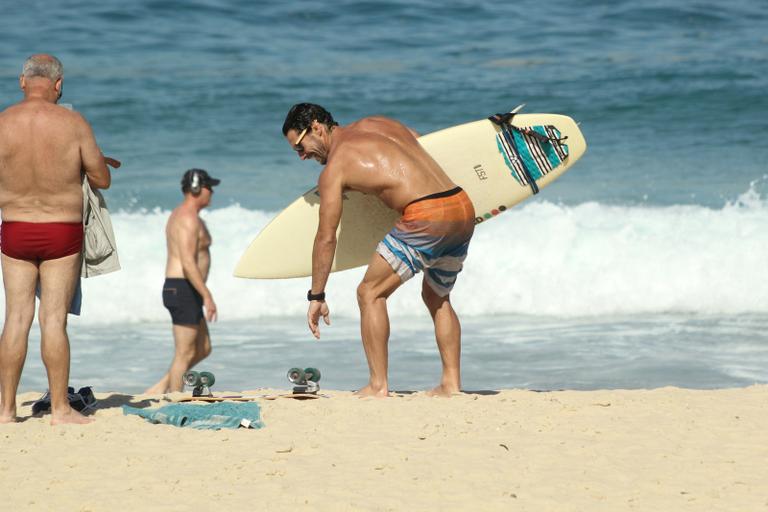 Flávio Canto exibe tanquinho em dia de surfe na praia