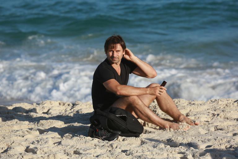 Sem desgrudar do celular, Murilo Rosa curte dia de praia no Rio de Janeiro