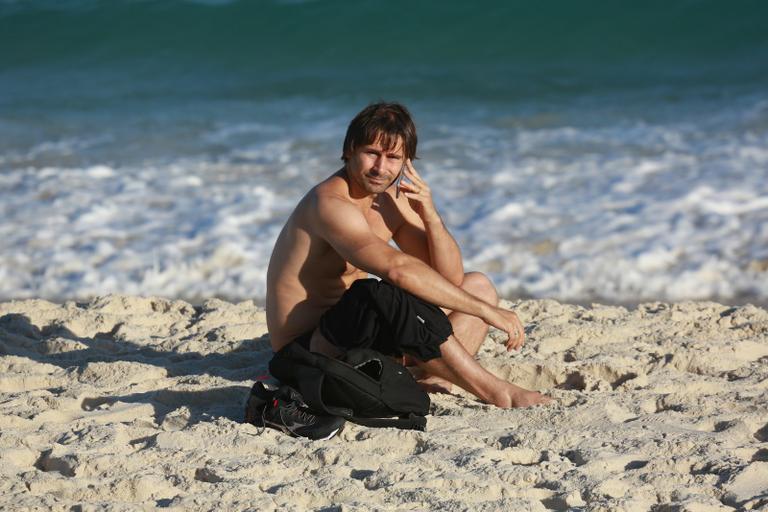 Sem desgrudar do celular, Murilo Rosa curte dia de praia no Rio de Janeiro