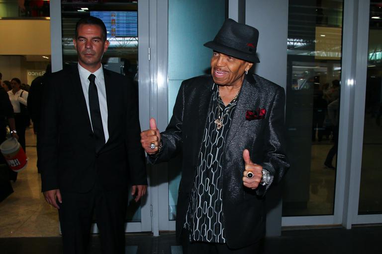 Joe Jackson chega sorridente a São Paulo acompanhado de seguranças