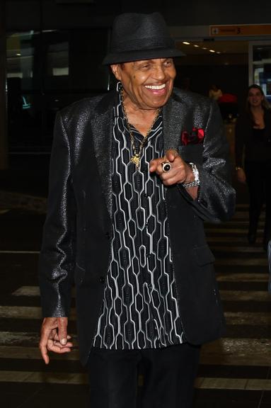 Joe Jackson chega sorridente a São Paulo acompanhado de seguranças