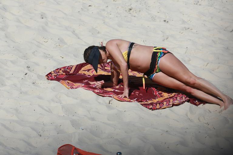 Deborah Secco exibe barrigão durante treino na praia