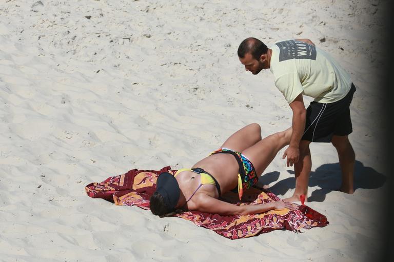 Deborah Secco exibe barrigão durante treino na praia