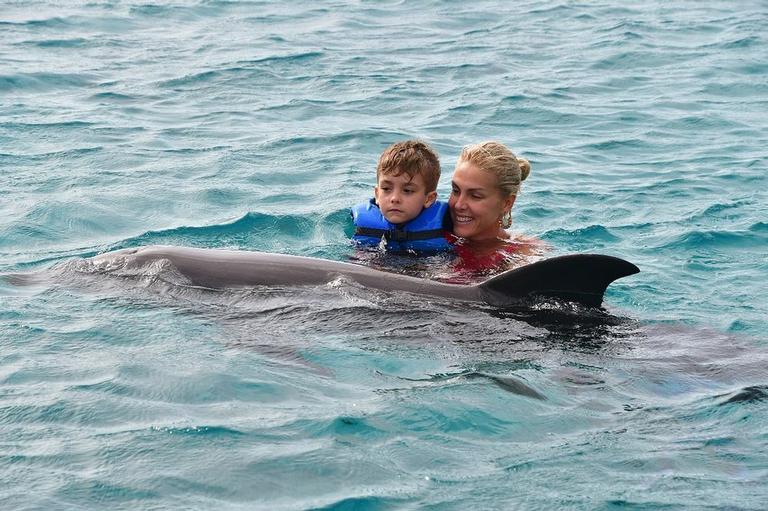 Ana Hickmann com o filho nadando com golfinhos