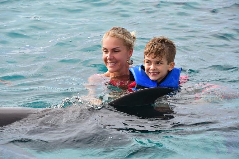 Ana Hickmann com o filho nadando com golfinhos