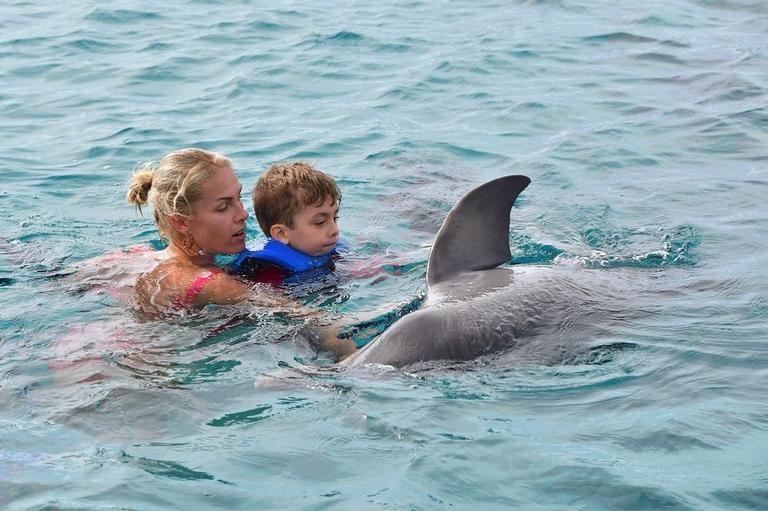 Ana Hickmann com o filho nadando com golfinhos