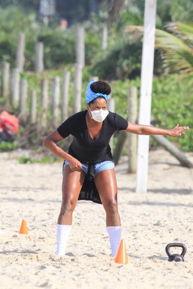 De máscara, Adriana Bombom treina na praia