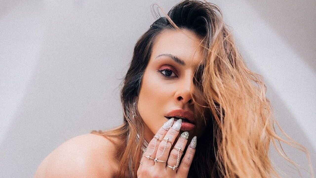 De vestido micro, Cleo exibe pernas tatuadas na cama