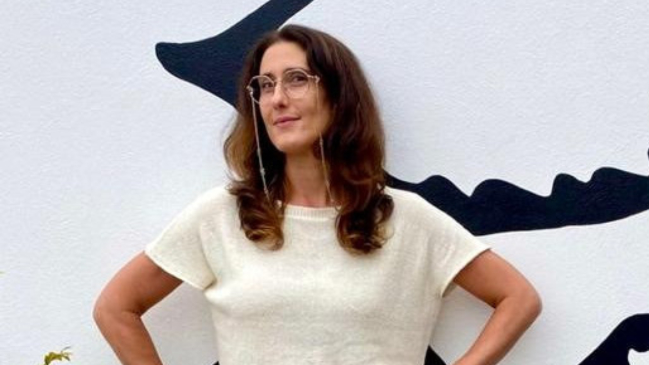De braços abertos e maiô azul, Paola Carosella posa sorridente no rio Paraguaçu