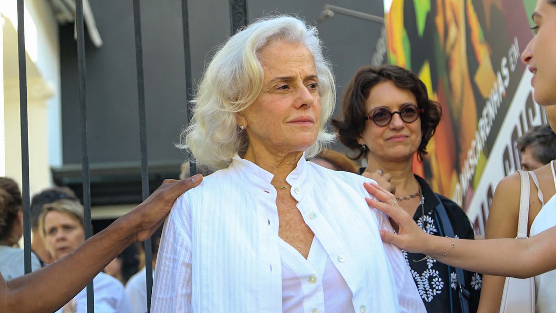 De branco, Marieta Severo é fotografada ao sair do velório do marido, Aderbal Freire-Filho