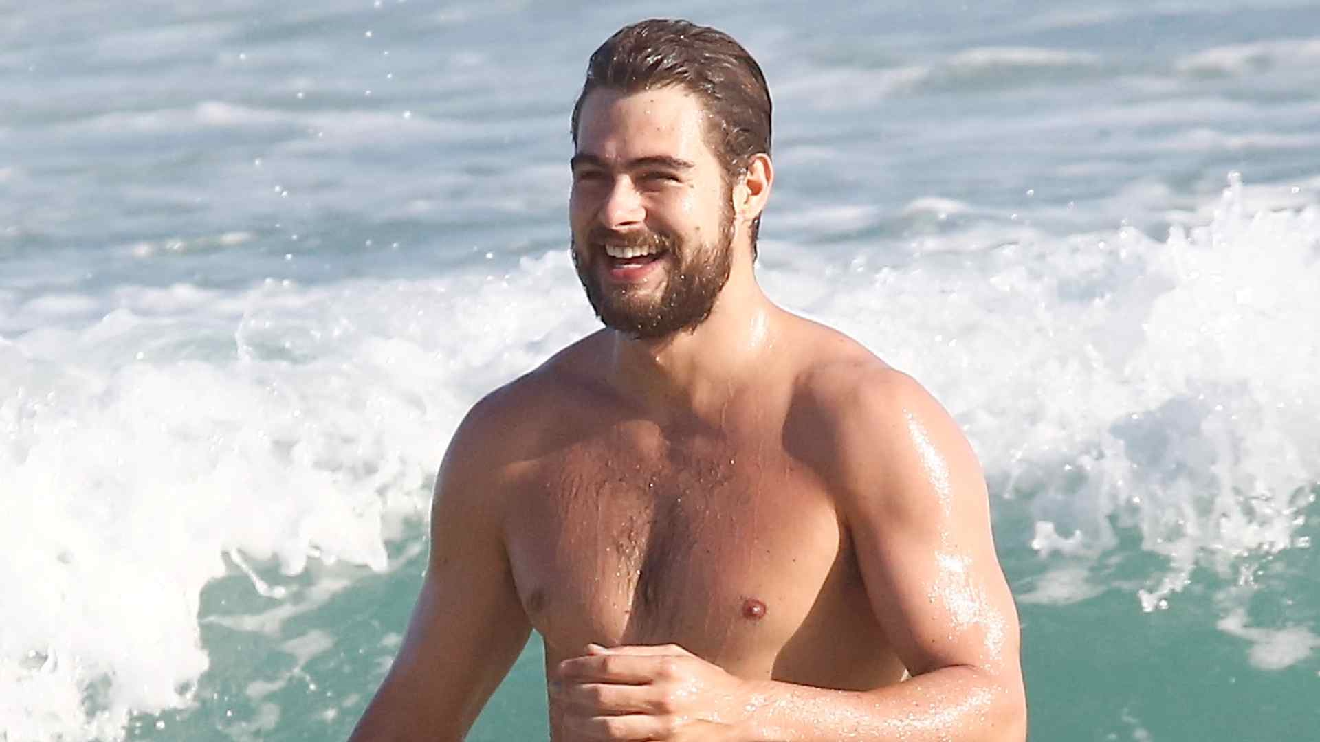 Sem camisa, Rafael Vitti aproveita o dia ensolarado na praia