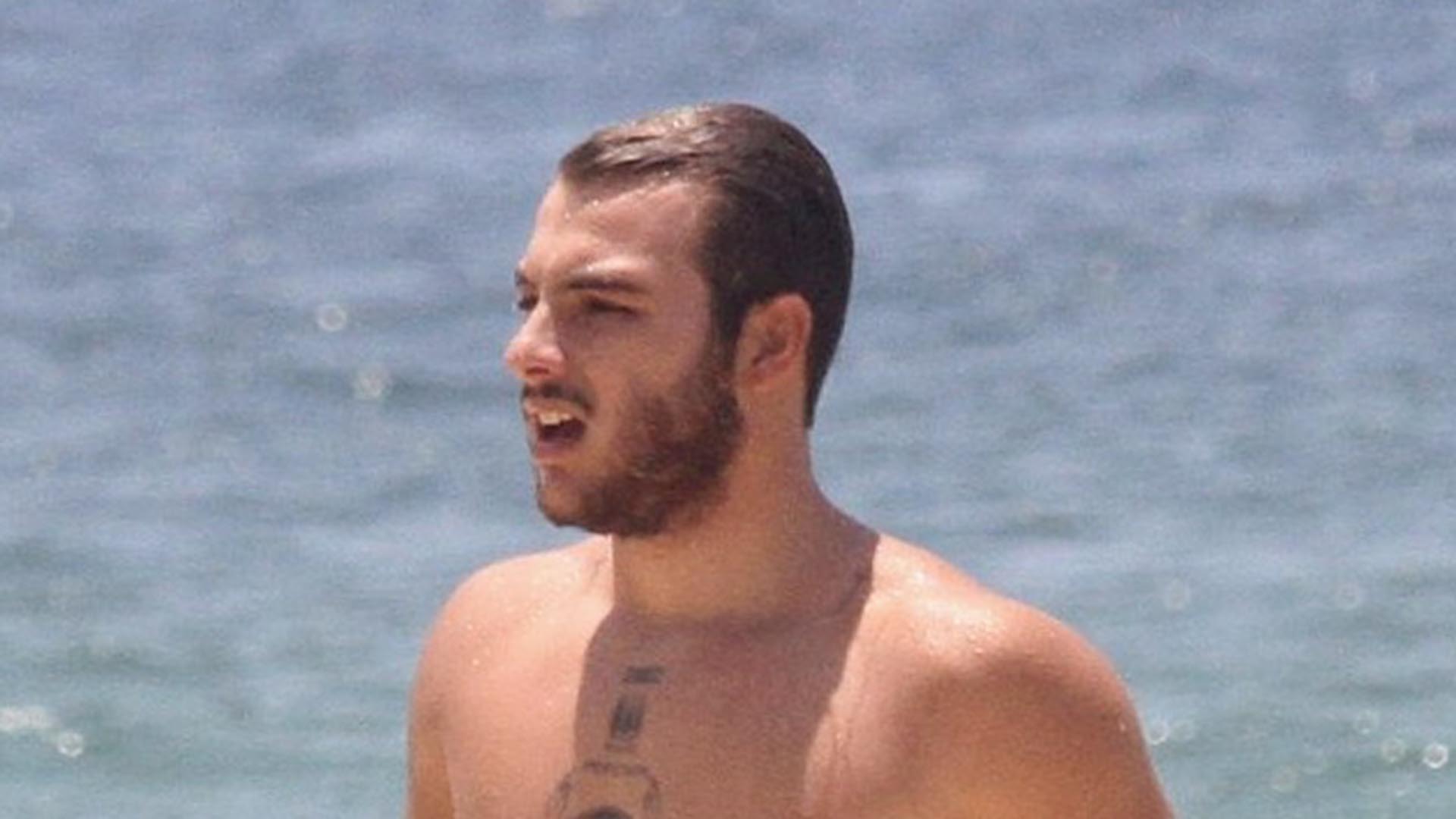 Sem camisa, filho de Patricia Poeta exibe suas tatuagens na praia