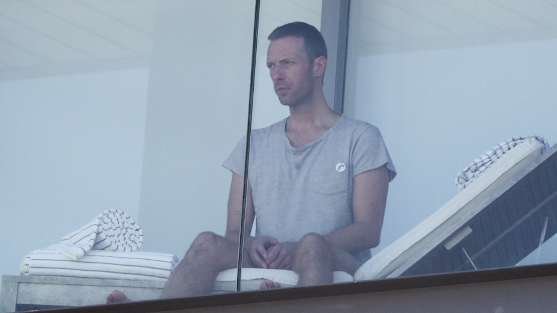 Chris Martin é flagrado à vontade, de shorts, na varanda de hotel do RJ