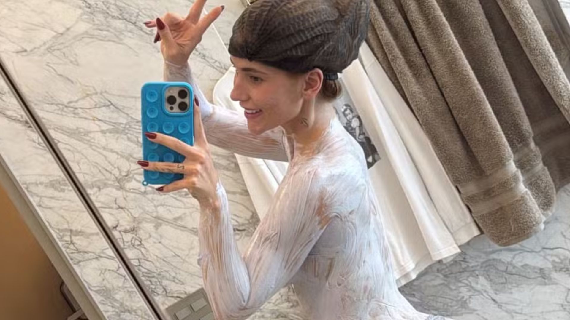 De toquinha, Virginia cobre o corpo todo de descolorante para se bronzear