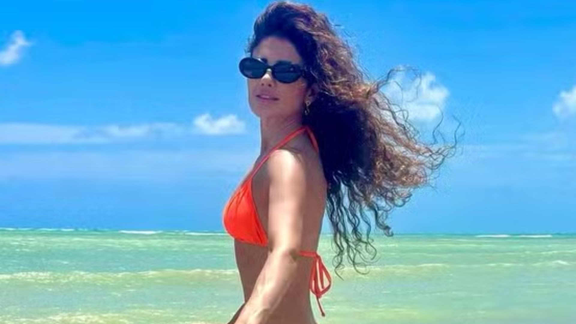 Paula Fernandes surge de biquíni laranja em passeio de bicicleta pela praia