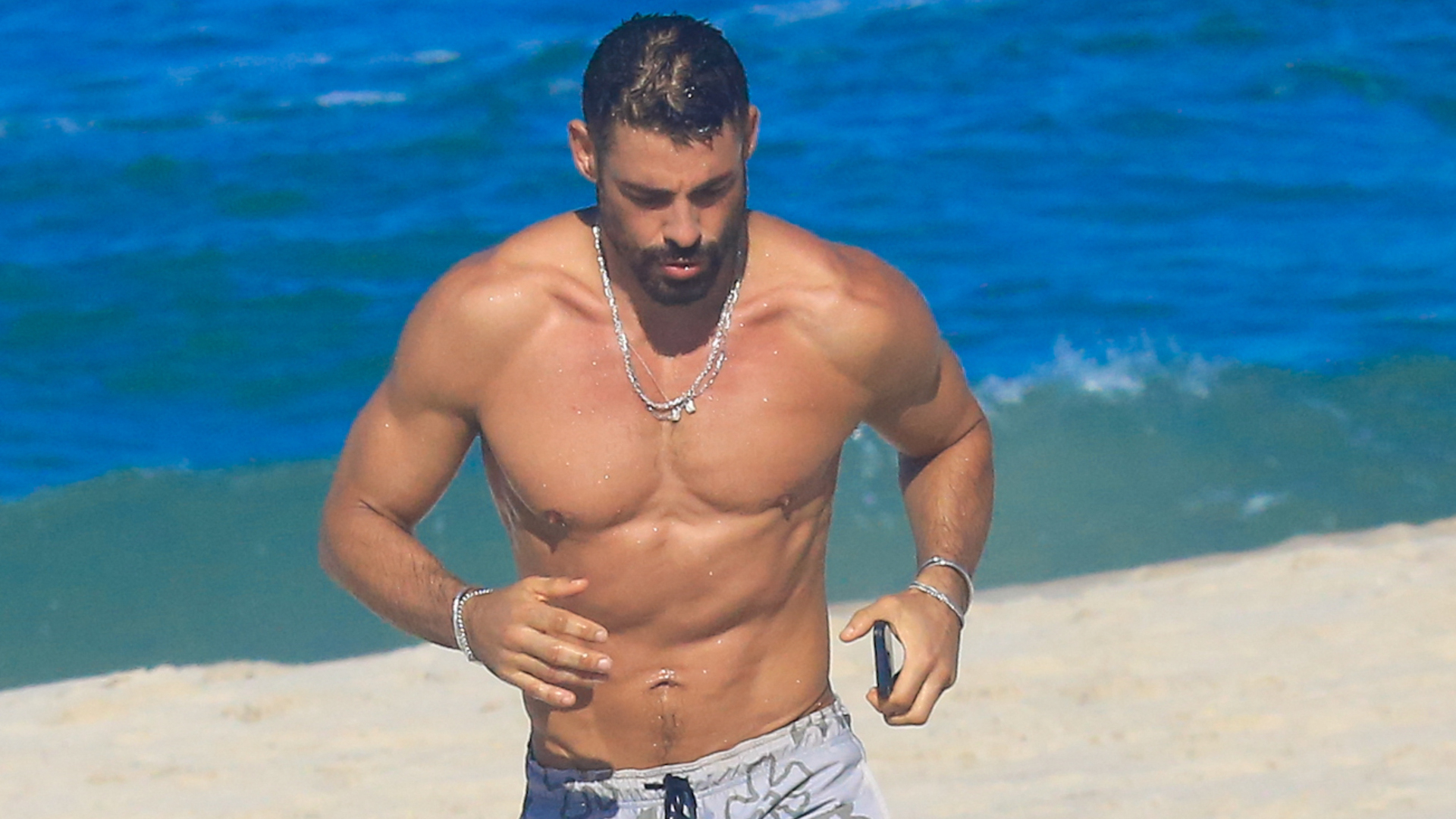 Cauã Reymond esbanja físico desenhado na praia e atende fãs; veja