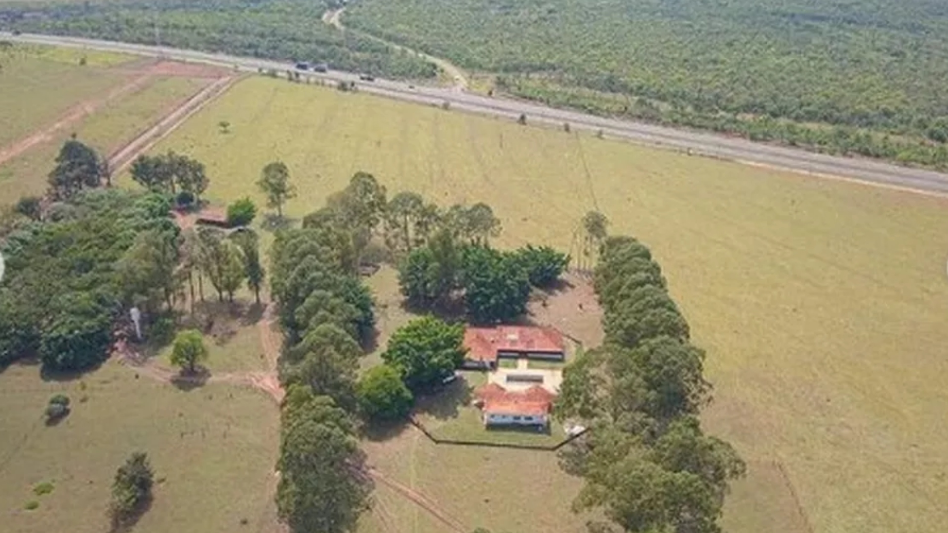 Vista panorâmica de fazenda no Pantanal com vegetação e áreas de pastagem para gado.